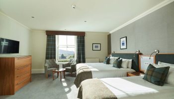 Crieff Hydro gay-friendly hotel room. Two beds, chairs, TV, and scenic view. Gay travel lodging with comfort, style, and Scottish charm.