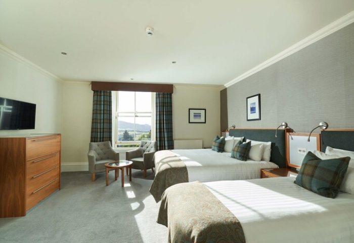 Crieff Hydro gay-friendly hotel room. Two beds, chairs, TV, and scenic view. Gay travel lodging with comfort, style, and Scottish charm.