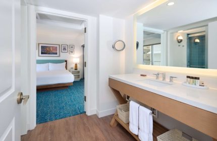 Outrigger Reef Waikiki Beach Resort: Gay-friendly hotel bathroom with vanity, mirror, and view into the bedroom. Ideal for gay travel.