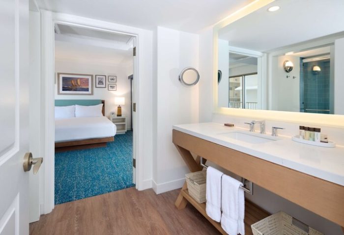 Outrigger Reef Waikiki Beach Resort: Gay-friendly hotel bathroom with vanity, mirror, and view into the bedroom. Ideal for gay travel.