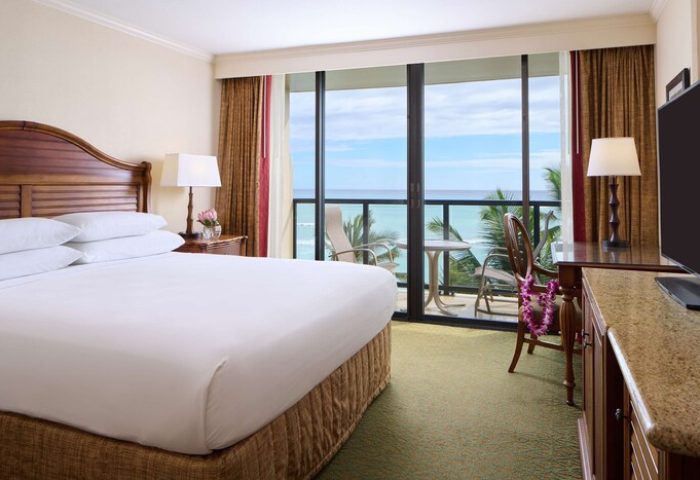 OUTRIGGER Waikiki Beach Resort gay-friendly hotel room. Ocean view from balcony. King bed, desk, TV, and chair with lei. Hawaii travel.