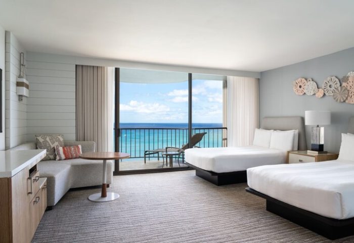 Waikiki Beach Marriott Resort & Spa gay-friendly hotel room with ocean view balcony. Two beds, couch, table, and chairs. Hawaii travel.