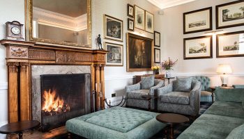Schloss Roxburghe Hotel's gay-friendly lounge. Fireplace, seating, and art create a cozy atmosphere. Ideal for gay men's travel and relaxation.