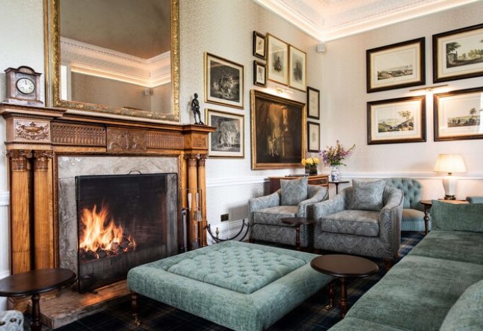 Schloss Roxburghe Hotel's gay-friendly lounge. Fireplace, seating, and art create a cozy atmosphere. Ideal for gay men's travel and relaxation.