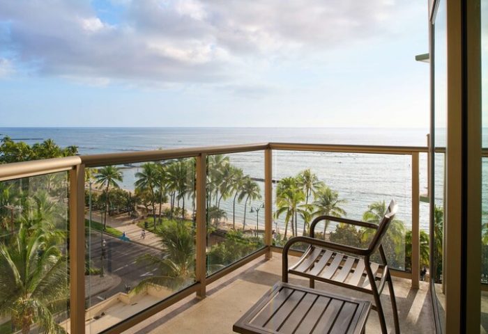 Aston Waikiki Circle Hotel balcony view. Gay-friendly hotel room overlooking Waikiki Beach, palm trees, and the Pacific Ocean. Relax on your gay vacation.