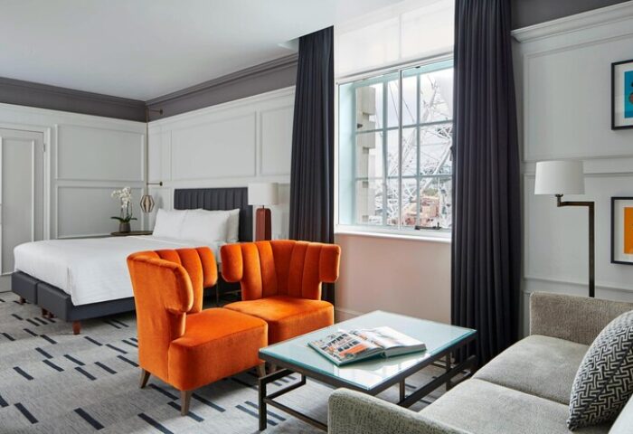 London Marriott Hotel County Hall gay-friendly room. Orange chairs, bed, and view of the London Eye. Stylish, modern gay hotel.