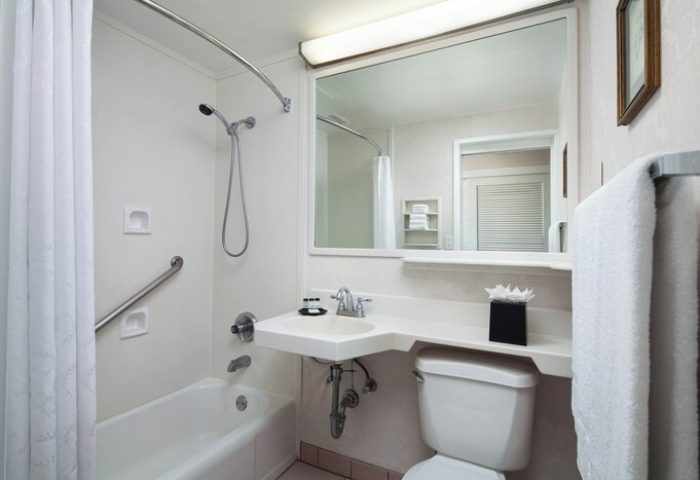 Bathroom at Sheraton Princess Kaiulani, a gay-friendly hotel. Features a shower with grab bar, sink, toilet, & mirror. Ideal for gay men travel.
