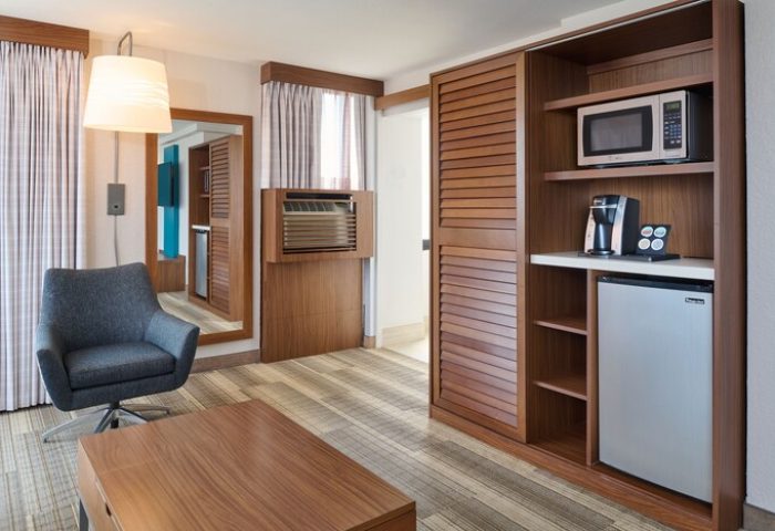 Holiday Inn Express Waikiki gay-friendly hotel room. Features include a chair, coffee table, mini fridge, microwave, and coffee maker.