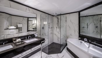 Fairmont St Andrews, Scotland gay-friendly hotel: Luxurious bathroom with marble walls, glass shower, double sink, and bathtub. Upscale travel.