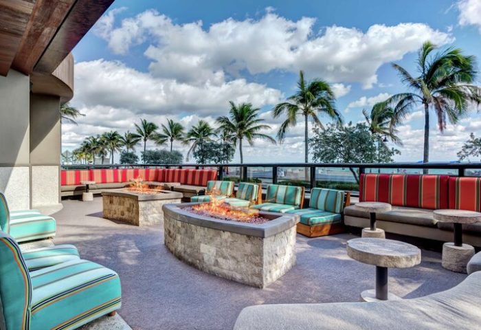 Hilton Fort Lauderdale Beach Resort gay-friendly hotel with outdoor lounge, fire pits, colorful seating, palm trees, and ocean view.