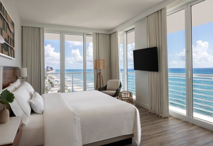 The Westin Fort Lauderdale Beach Resort gay-friendly hotel room with ocean view. Balcony, bed, TV, and chair. Modern design, relaxing atmosphere.