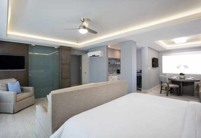 Elita Hotel gay-friendly suite. Modern room with kitchenette, dining area, and seating. Ideal for gay men's travel. Upscale hotel interior.