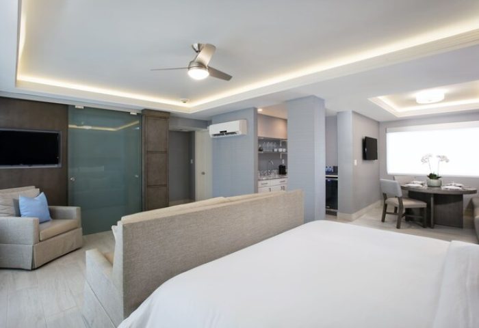 Elita Hotel gay-friendly suite. Modern room with kitchenette, dining area, and seating. Ideal for gay men's travel. Upscale hotel interior.