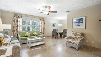 Coconut Bay Resort gay-friendly hotel suite living area. Wicker furniture, dining table, floral decor. Ideal for gay men's travel.
