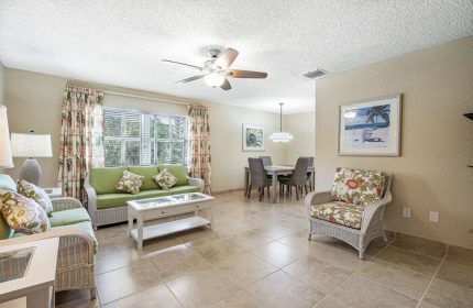 Coconut Bay Resort gay-friendly hotel suite living area. Wicker furniture, dining table, floral decor. Ideal for gay men's travel.
