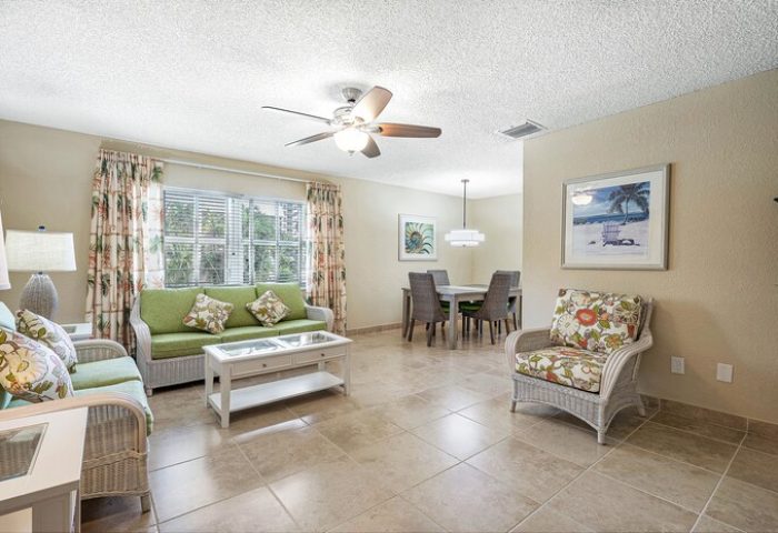 Coconut Bay Resort gay-friendly hotel suite living area. Wicker furniture, dining table, floral decor. Ideal for gay men's travel.