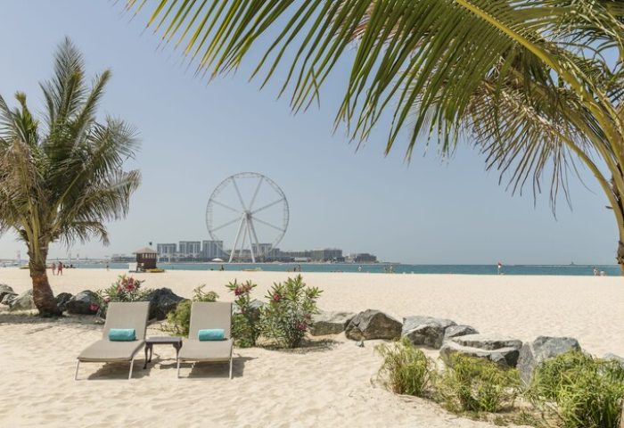 Le Royal Méridien Beach Resort & Spa: Beach view with loungers, palm trees, and the Ain Dubai ferris wheel. Gay-friendly hotel.