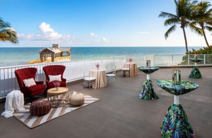 The Reach Key West, Curio Collection by Hilton, a gay-friendly hotel. Ocean view from the terrace with tables and chairs. Pier in the background.