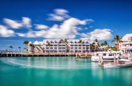 Opal Key Resort & Marina, a gay-friendly hotel. Waterfront view with boats docked, palm trees, and blue sky. Ideal for gay travel advice.