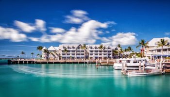 Opal Key Resort & Marina, a gay-friendly hotel. Waterfront view with boats docked, palm trees, and blue sky. Ideal for gay travel advice.
