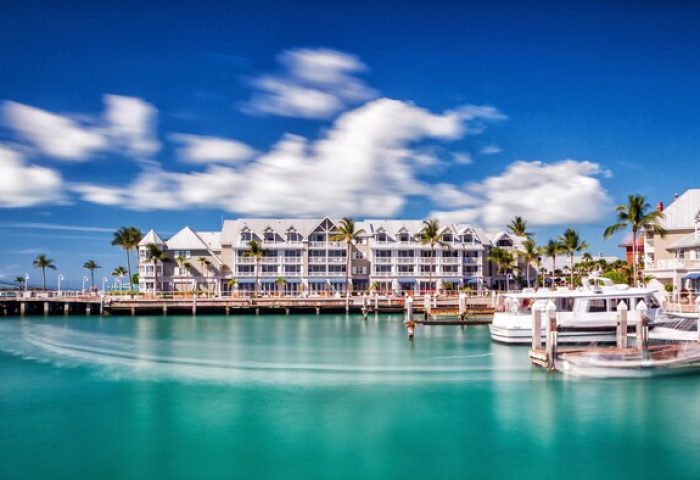 Opal Key Resort & Marina, a gay-friendly hotel. Waterfront view with boats docked, palm trees, and blue sky. Ideal for gay travel advice.