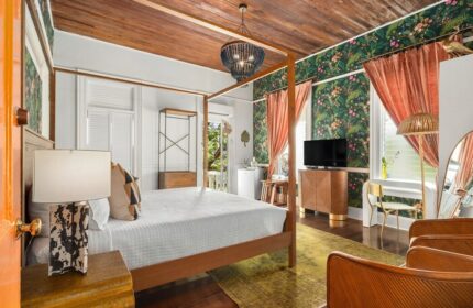Marrero's Guest Mansion gay-friendly hotel room. Four-poster bed, tropical wallpaper, and stylish decor for gay men's travel in Key West.