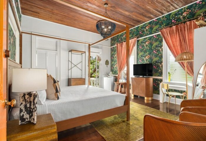 Marrero's Guest Mansion gay-friendly hotel room. Four-poster bed, tropical wallpaper, and stylish decor for gay men's travel in Key West.