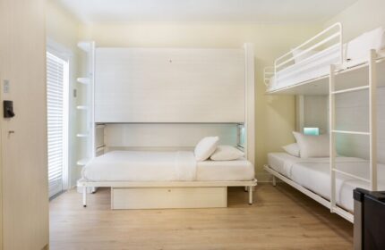NYAH Key West Gay-Friendly Hotel room. White Murphy bed and bunk beds with white linens. Adults-only lodging for gay men's travel.
