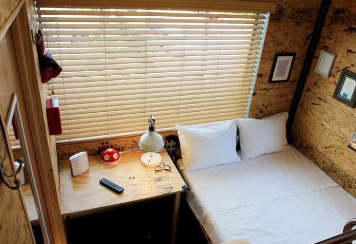 Gaythering Hotel crate room interior. Small room with bed, desk, and quirky decor. Gay-friendly travel lodging.