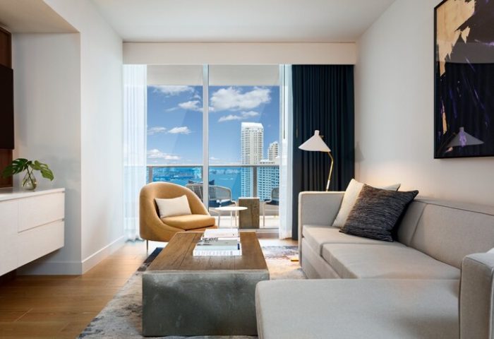 Kimpton EPIC Hotel gay-friendly room. Modern living room with a view of Miami's skyline and ocean. Stylish, comfortable, and inviting for gay travelers.