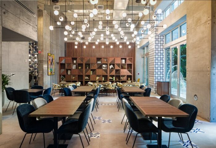 Hotel Indigo Miami Brickell gay-friendly hotel dining area. Tables with blue chairs, modern lighting, and geometric shelving. Stylish, welcoming space.
