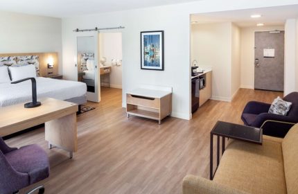 Hampton Inn & Suites Miami/Brickell-Downtown gay-friendly hotel suite. Bedroom, desk, kitchenette, and seating area. Modern decor.