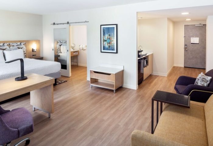 Hampton Inn & Suites Miami/Brickell-Downtown gay-friendly hotel suite. Bedroom, desk, kitchenette, and seating area. Modern decor.