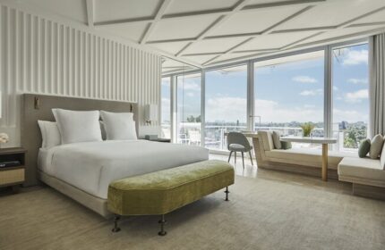 Four Seasons Hotel at The Surf Club room. Gay-friendly hotel bedroom with large windows, bed, bench, and seating area. Luxury travel.