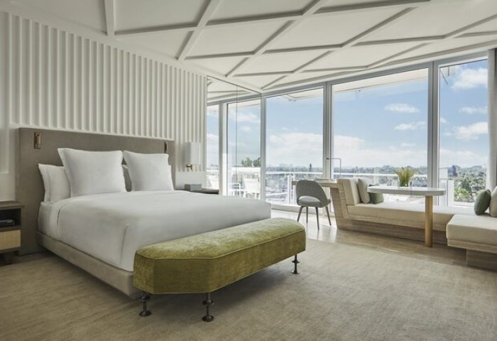 Four Seasons Hotel at The Surf Club room. Gay-friendly hotel bedroom with large windows, bed, bench, and seating area. Luxury travel.