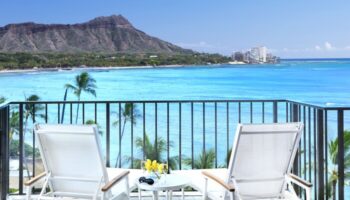 Halekulani Hotel balcony view. Gay-friendly hotel with ocean, Diamond Head, and lounge chairs. Ideal for gay men's travel in Honolulu.