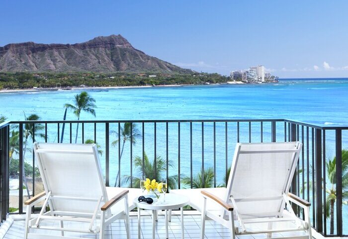 Halekulani Hotel balcony view. Gay-friendly hotel with ocean, Diamond Head, and lounge chairs. Ideal for gay men's travel in Honolulu.