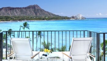 Halekulani Hotel balcony view. Gay-friendly hotel with ocean, Diamond Head, and lounge chairs. Ideal for gay men's travel in Honolulu.