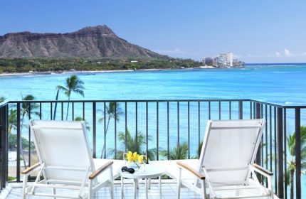 Halekulani Hotel balcony view. Gay-friendly hotel with ocean, Diamond Head, and lounge chairs. Ideal for gay men's travel in Honolulu.