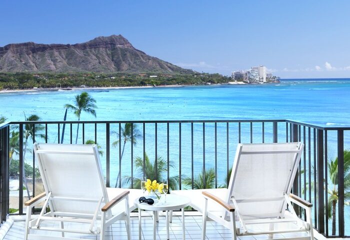 Halekulani Hotel balcony view. Gay-friendly hotel with ocean, Diamond Head, and lounge chairs. Ideal for gay men's travel in Honolulu.