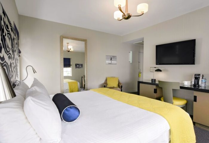 Hotel Breakwater South Beach room. Gay-friendly hotel bedroom with bed, desk, chair, TV, and mirror. Modern design, bright colors, and comfortable.