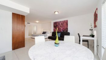 Strand Ocean Drive Suites gay-friendly hotel room. Features a bed, sofa, desk, and round table. Modern design, ideal for gay travelers.