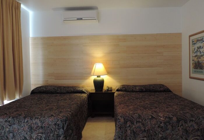 James Hotel gay-friendly room with two beds, nightstand, and lamp. Comfortable lodging for gay men travelers.