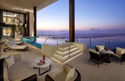 Atlantis The Royal gay-friendly hotel suite. Balcony with pool, lounge chairs, seating area, and city view. Luxury gay travel in Dubai.