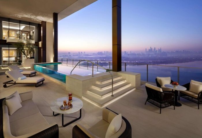 Atlantis The Royal gay-friendly hotel suite. Balcony with pool, lounge chairs, seating area, and city view. Luxury gay travel in Dubai.