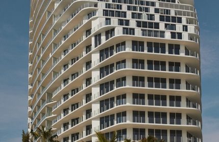 Four Seasons Hotel and Residences Fort Lauderdale, a gay-friendly hotel. Tall, white building with palm trees against a clear blue sky.