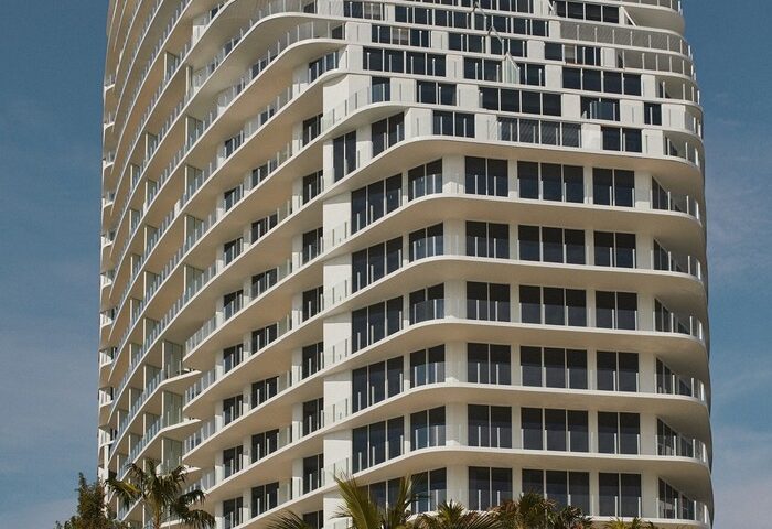 Four Seasons Hotel and Residences Fort Lauderdale, a gay-friendly hotel. Tall, white building with palm trees against a clear blue sky.
