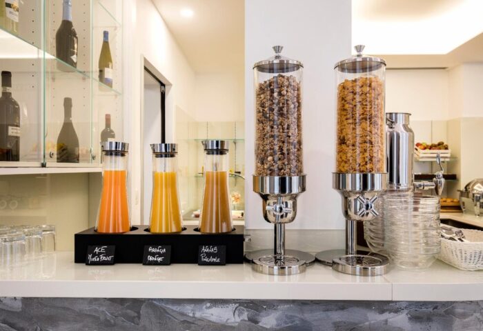 Breakfast bar at 43 Station Hotel, a gay-friendly hotel. Juice dispensers, cereal containers, and glassware provide a welcoming start to the day.