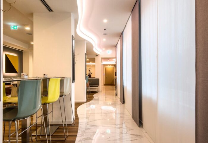 43 Station Hotel interior view. Gay-friendly hotel hallway with marble floors, modern lighting, & colorful bar stools. A welcoming space for gay travelers.