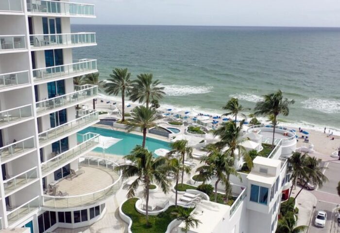 Hilton Fort Lauderdale Beach Resort view. Palm trees, pool, and ocean. Gay-friendly hotel for gay men travel advice in Florida.